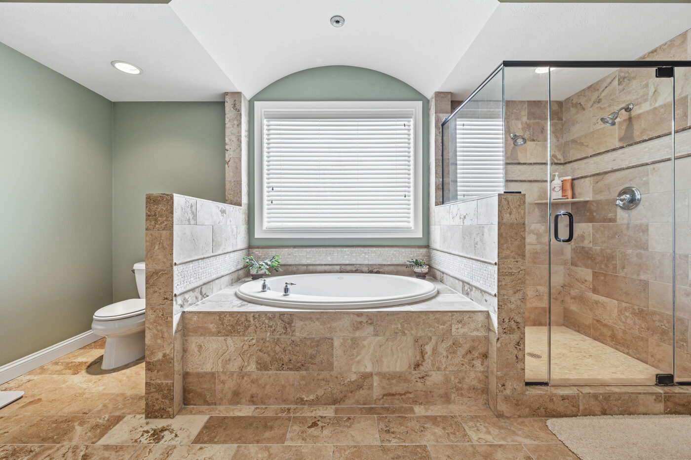 Primary bathroom soaking tub in vaulted travertine niche
